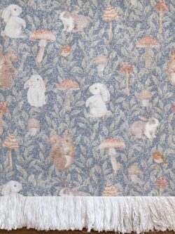 Alfombra tejida de diseño infantil de conejos y ardillas, hongos y enredadera de hojas con fondo jean azul.